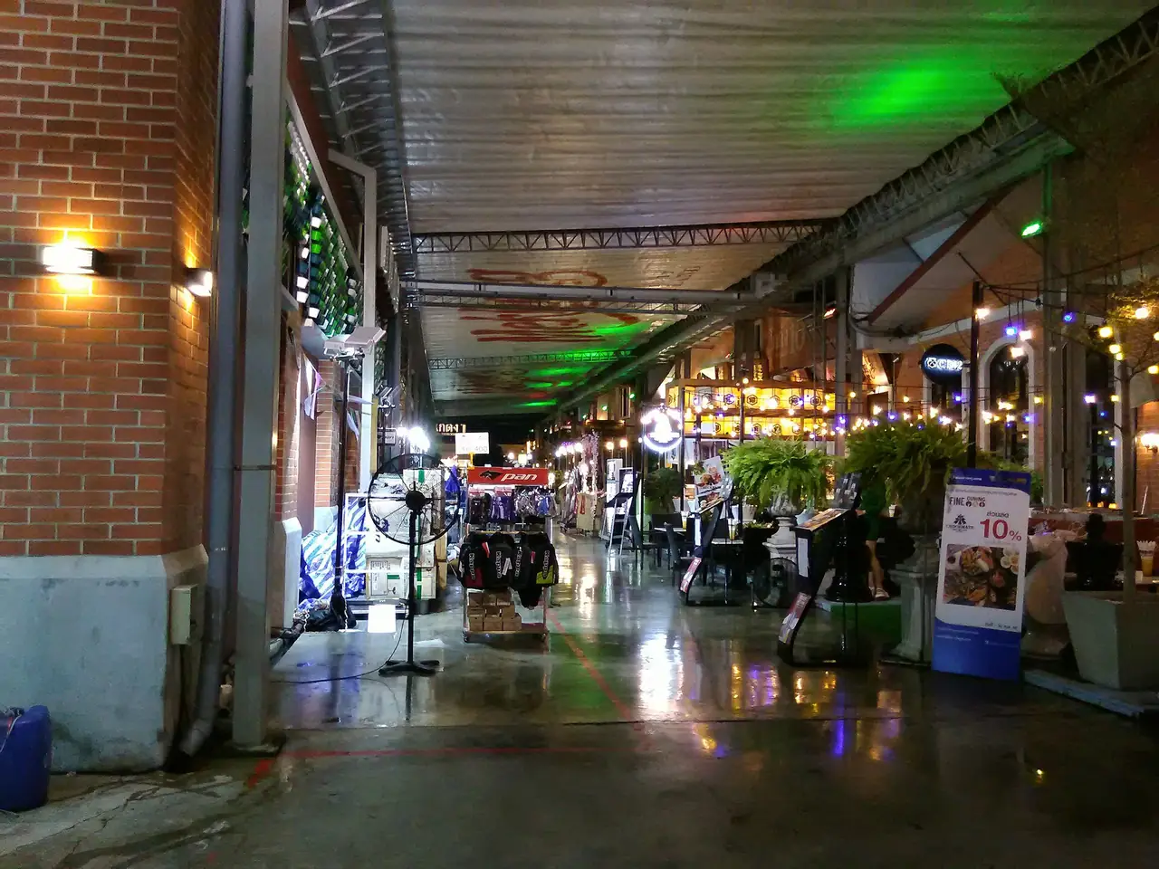 A covered walkway between the old warehouses at Asiatique, lit at night