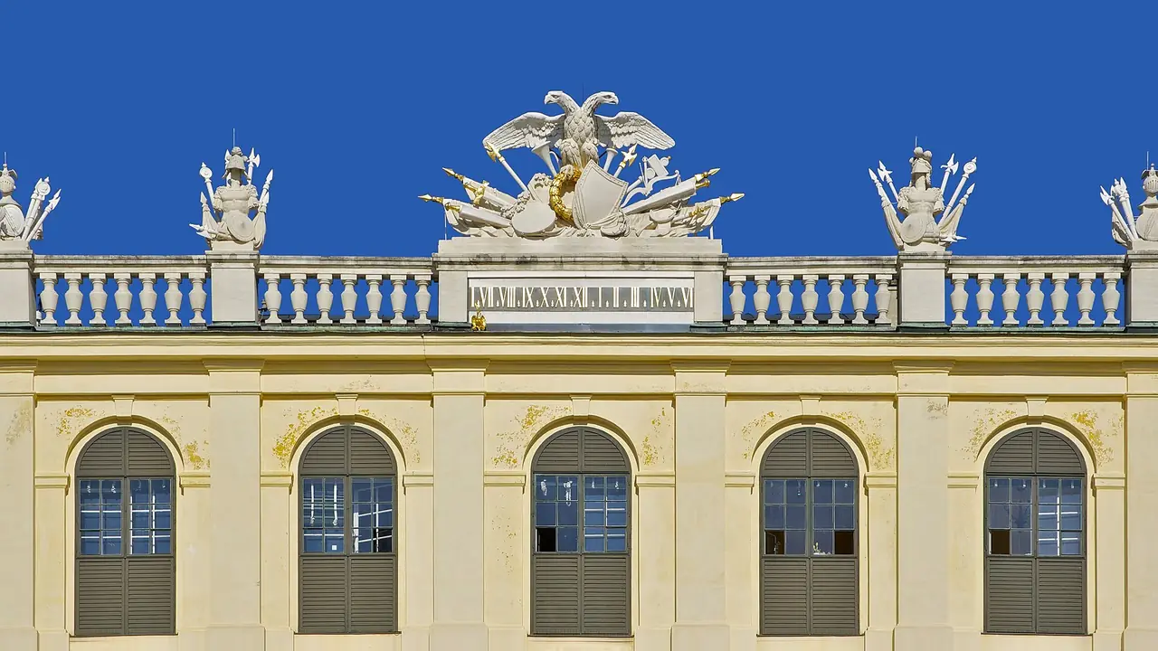 นาฬิกาและงานประดับบนด้านหน้าพระราชวังเชินบรุนน์ ภาพถ่ายจาก Wikimedia Commons