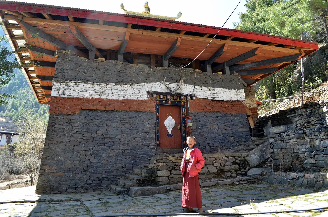 วัดดำ Lhakhang Nagpo ผนังหินสีเข้มและเด็กพระยืนหน้าประตู ภาพจาก Wikimedia Commons ผู้ถ่าย Christopher J. Fynn สัญญา CC BY-SA 3.0