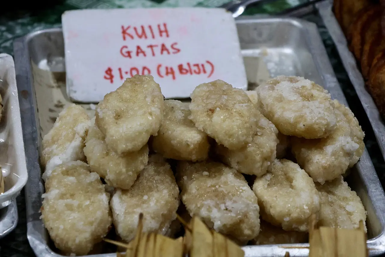 ขนมกูอิห์กาตัสที่ป้ายบอกราคา 1 ดอลลาร์ต่อสี่ชิ้น ที่ตลาดกลางคืนกาดง ภาพจาก Wikimedia Commons ผู้ถ่าย Pangalau สัญญา CC BY-SA 4.0 ถ่าย 4 ต.ค. 2567 ตามชื่อไฟล์ ราคาในป้ายเป็นราคาวันที่ถ่ายเท่านั้น