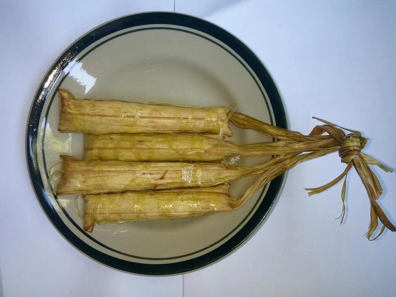 ขนมข้าวเหนียวห่อใบไม้มัดเชือกวางบนจาน ตามชื่อไฟล์คือกือลูปิส (kelupis) ภาพจาก Wikimedia Commons ผู้ถ่าย Night Lantern สัญญา CC BY-SA 4.0