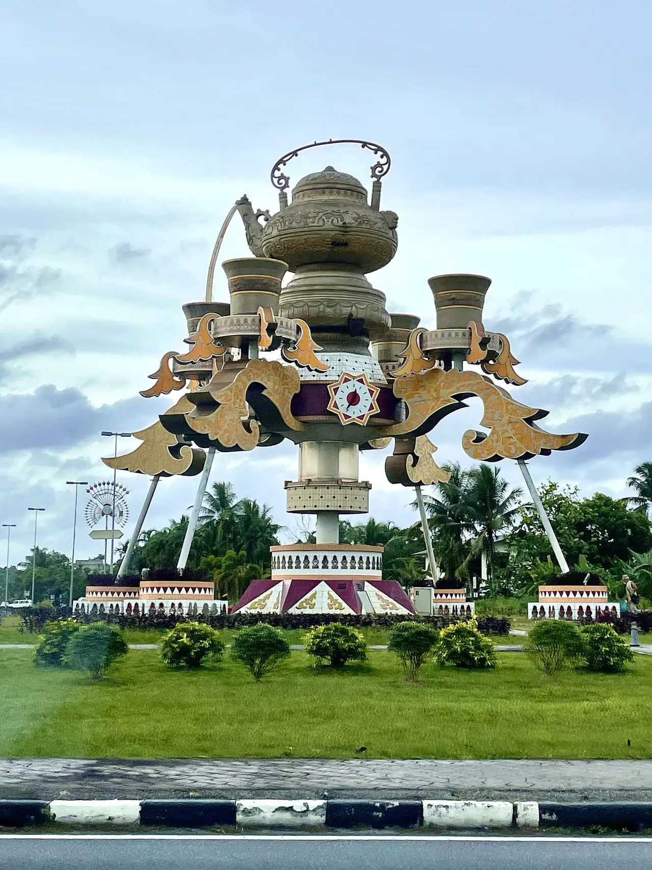 กาน้ำชายักษ์ Kiri Monument ที่วงเวียนในกัวลาเบไลต์ กาน้ำชาตั้งบนฐานและถ้วยสี่ใบรอบ ภาพจาก Wikimedia Commons ผู้ถ่าย DeltaSquad833 สัญญา CC BY-SA 4.0