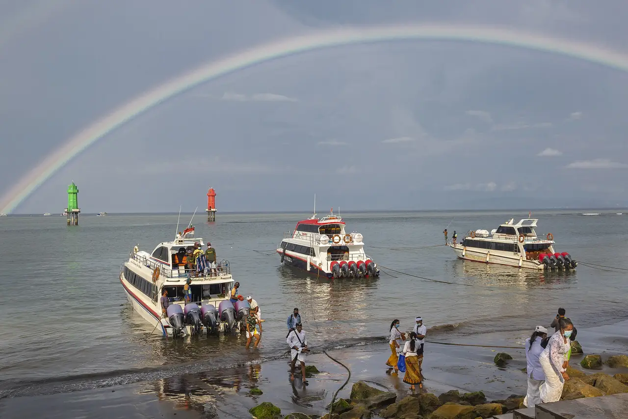 เรือเร็วจอดที่ท่าเรือซานูร์ มีรุ้งกินน้ำเหนือทะเล (ภาพท่าเรือ)