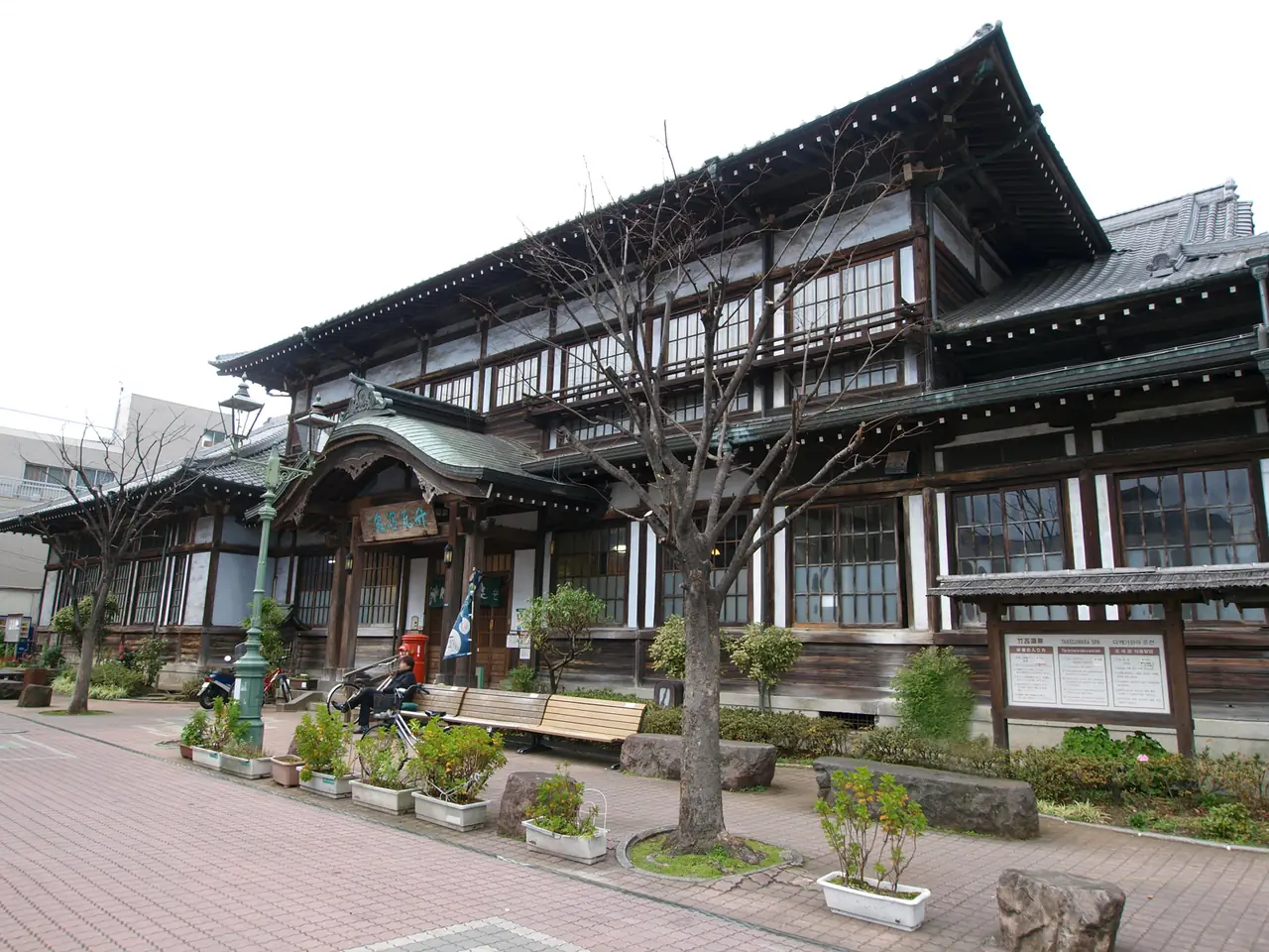 Takegawara Onsen มองจากด้านข้าง เห็นหลังคาและต้นไม้หน้าอาคาร (ภาพสถานที่)
