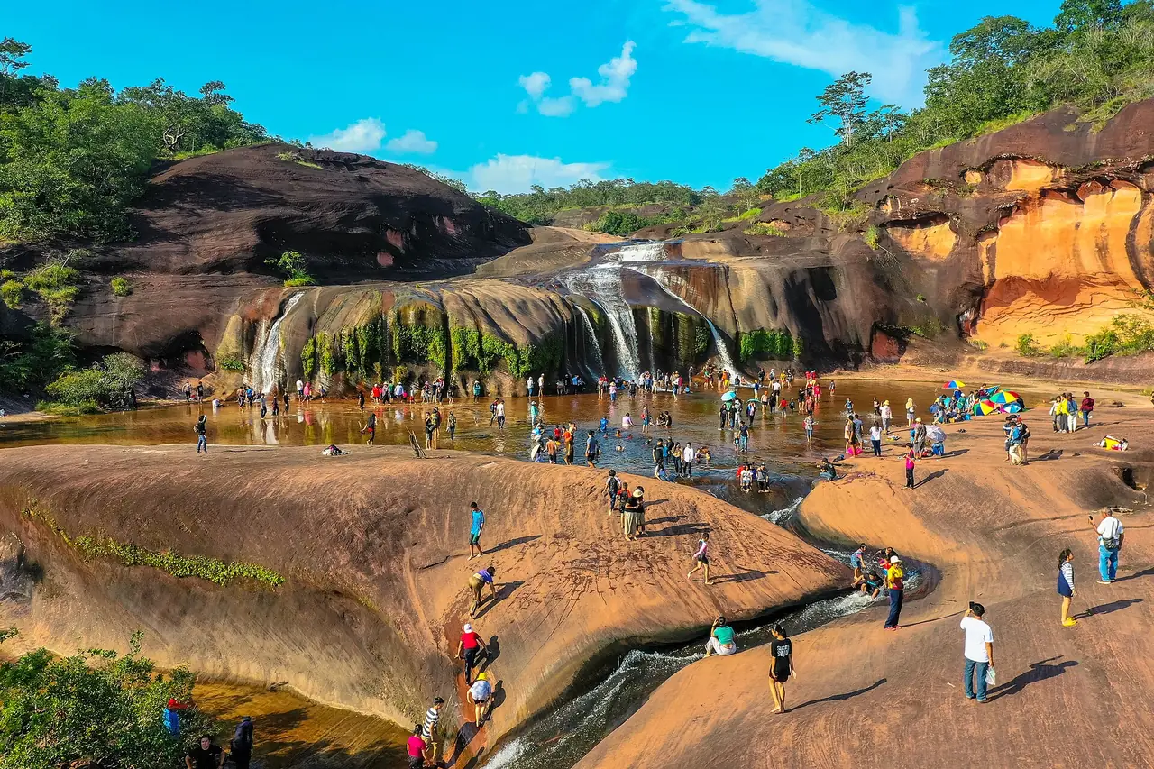 น้ำตกถ้ำพระในเขตรักษาพันธุ์สัตว์ป่าภูวัว มีผู้คนเล่นน้ำที่ลานหิน