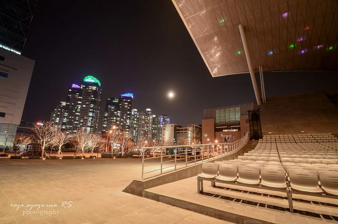 โรงภาพยนตร์กลางแจ้ง Busan Cinema Center ยามค่ำ มีตึกสูงของเซ็นทัมซิตี้อยู่ด้านหลัง