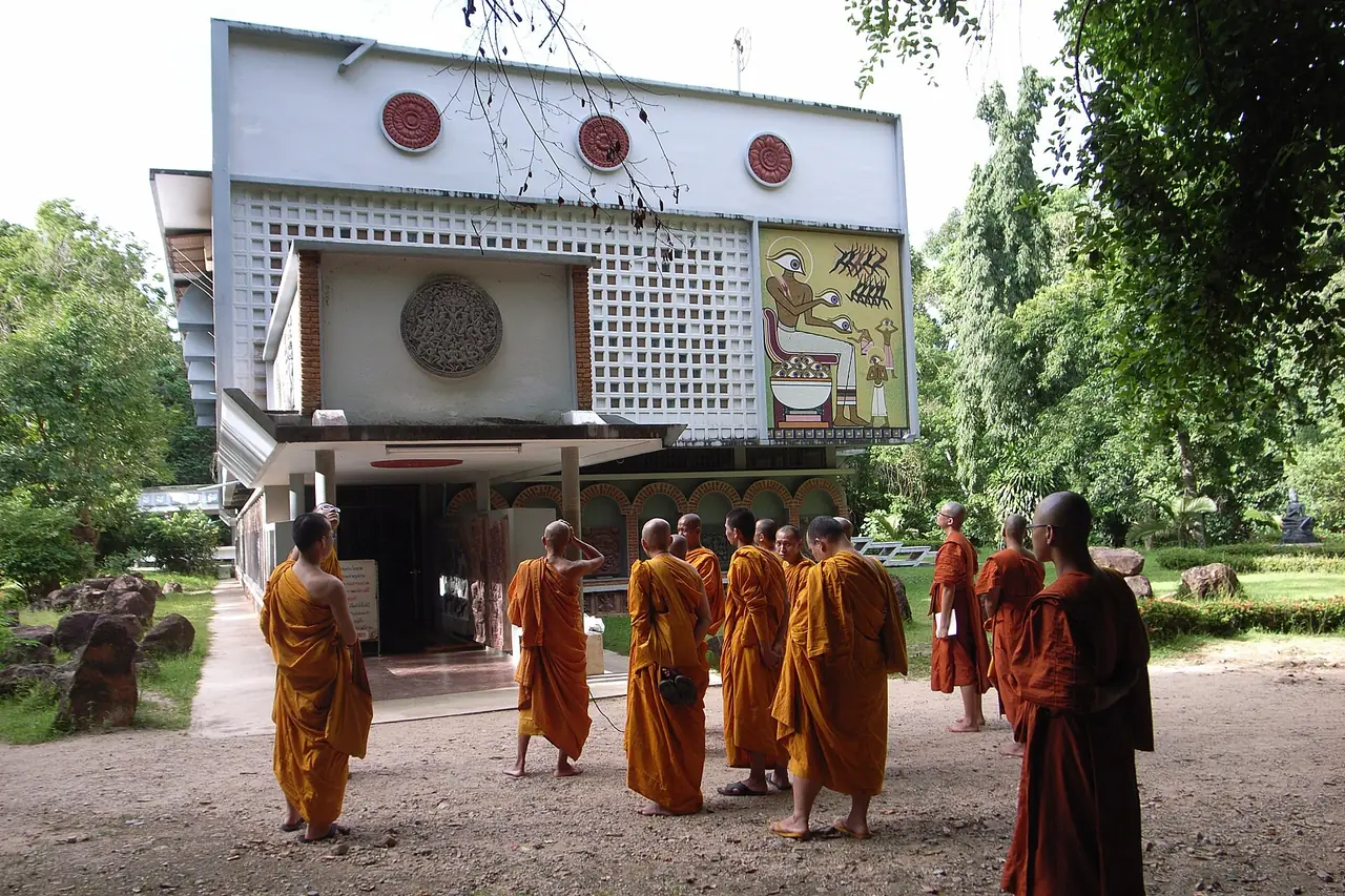 โรงละครแห่งจิตวิญญาณ สวนโมกข์ พร้อมพระสงฆ์ยืนอยู่ด้านหน้า ภาพของ Wit Pimkanchanapong จาก Wikimedia Commons ไม่ได้ระบุปีที่ถ่าย