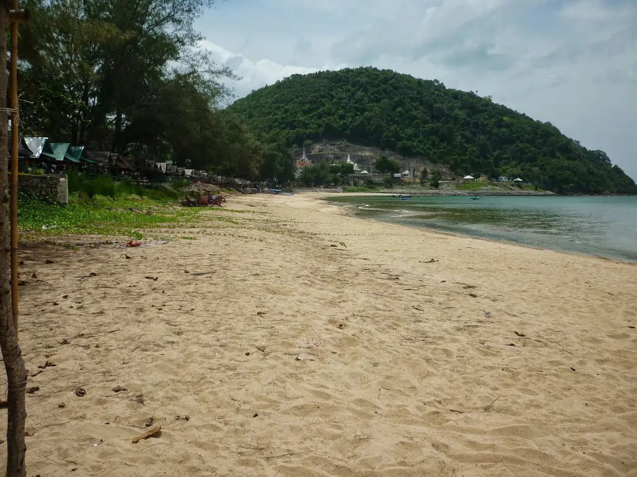 หาดทรายรี มีแหลมที่ปกคลุมด้วยต้นไม้และวัดบนเนินอยู่ด้านหลัง