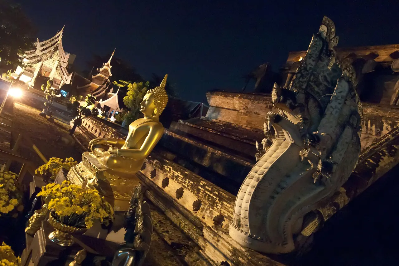 Wat Chedi Luang at night, with a Buddha image and naga rails on the chedi stairs