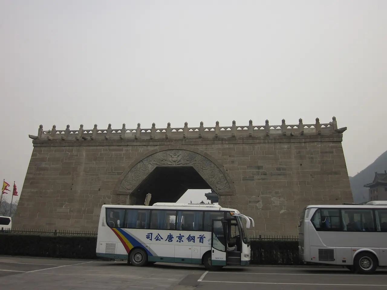 ประตูโค้งหินที่เรียกว่าเมฆา (云台 Yuntai) ของจวีย์ยงกวน มีรถทัวร์จอดด้านหน้า ภาพจาก Wikimedia Commons ผู้ถ่าย Huangdan2060 สัญญา CC0 ไม่ได้ระบุปีที่ถ่ายจากข้อมูลที่เห็น