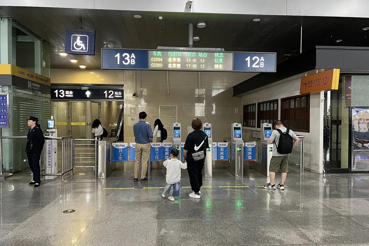 ประตูตรวจตั๋ว 12 และ 13 ในห้องรอใต้ดินของสถานีเทียนจิน ป้ายระบุขบวนไปปักกิ่งใต้ ภาพจาก Wikimedia Commons ผู้ถ่าย N509FZ สัญญา CC BY-SA 4.0 ถ่ายเดือนพฤษภาคม 2567