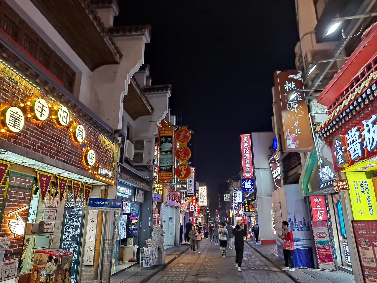 ถนนไท่ผิงยามค่ำคืน มีป้ายร้านและแผงอาหารเรียงสองข้างทาง ภาพจาก Wikimedia Commons ผู้ถ่าย EditQ สัญญา CC BY-SA 4.0 ไม่ระบุปีถ่าย