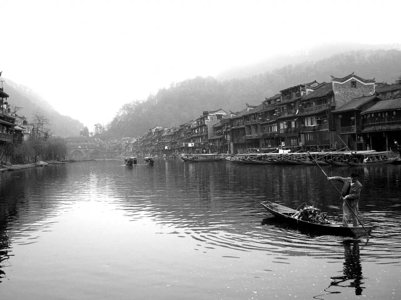 ชายพายเรือบนแม่น้ำถัวเจียงหน้าบ้านริมน้ำ ภาพขาวดำ ภาพจาก Wikimedia Commons ผู้ถ่าย Robert Baxter สัญญา CC0 ไม่ระบุปีถ่าย