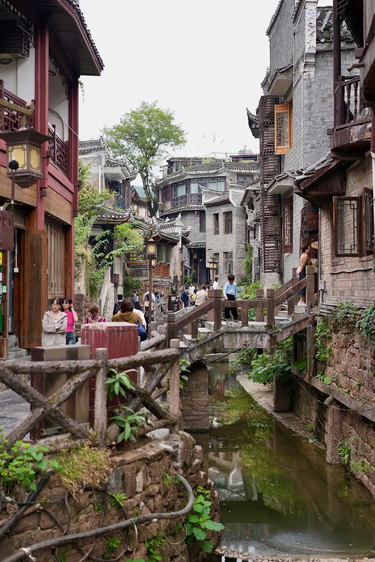 ตรอกริมคลองในเมืองเก่าเฟิ่งหวง มีบันไดไม้และบ้านเก่าสองข้างทาง ภาพจาก Wikimedia Commons ผู้ถ่าย Lianguanlun สัญญา CC BY 4.0 ไม่ระบุปีถ่าย