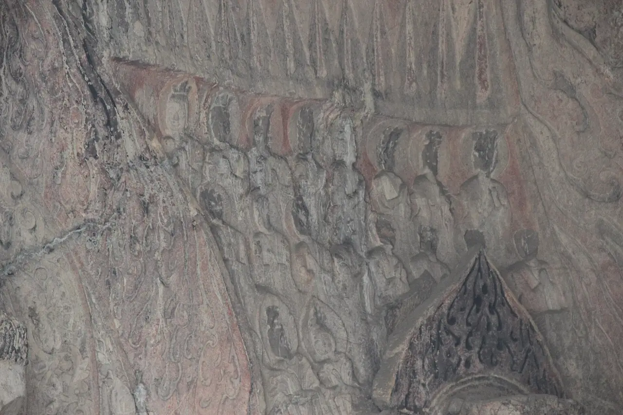 ลายนูนบนเพดานด้านในถ้ำปินหยาง มีแถวพระพุทธรูปและลายประดับ สีแดงที่เห็นเป็นร่องรอยสีเก่า ภาพจาก Wikimedia Commons ผู้ถ่าย Gary Todd สัญญา CC0