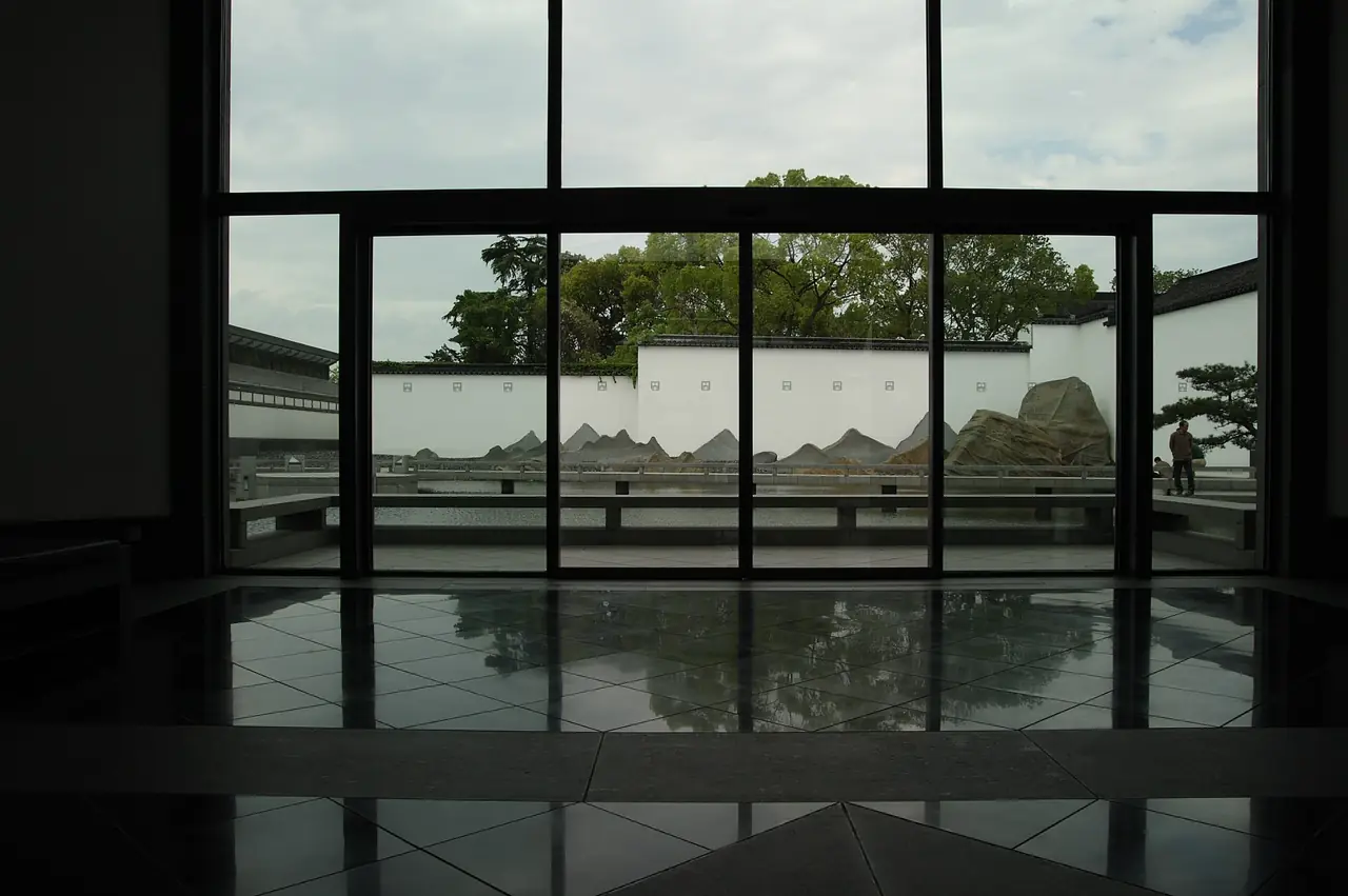 ลานหินจัดสวนสีขาวเทามองผ่านกระจกบานใหญ่ของพิพิธภัณฑ์ซูโจว ภาพจาก Wikimedia Commons ผู้ถ่าย shadowx1978 สัญญา CC BY 2.0 ไม่ระบุปีที่ถ่าย ภาพนี้เป็นภายในอาคารที่ออกแบบโดย I. M. Pei