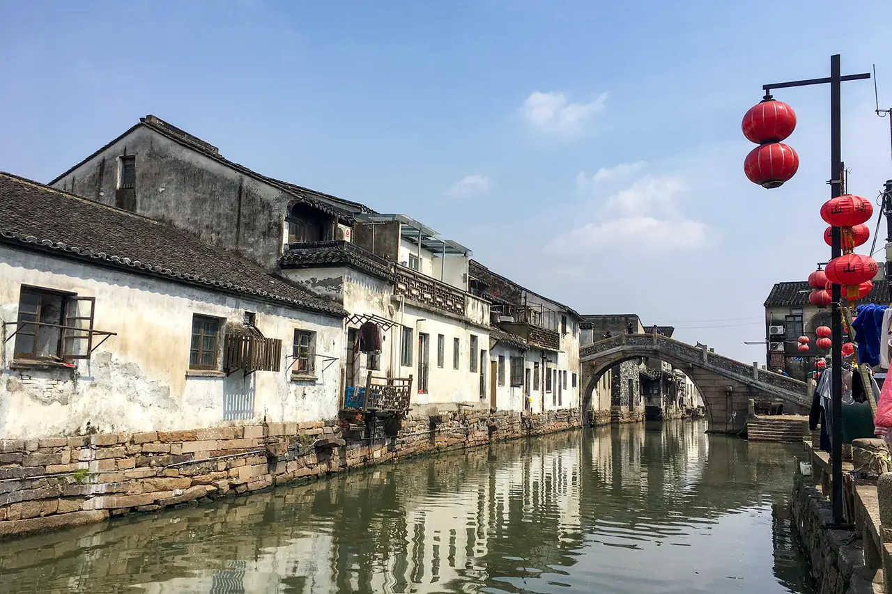 คลองซานถังกับบ้านเรือนริมน้ำและสะพานหินโค้ง มีโคมแดงแขวนที่ริมถนน ภาพจาก Wikimedia Commons ผู้ถ่าย Windmemories สัญญา CC BY-SA 4.0 ภาพวันที่ 17 เม.ย. 2560 ตามชื่อไฟล์