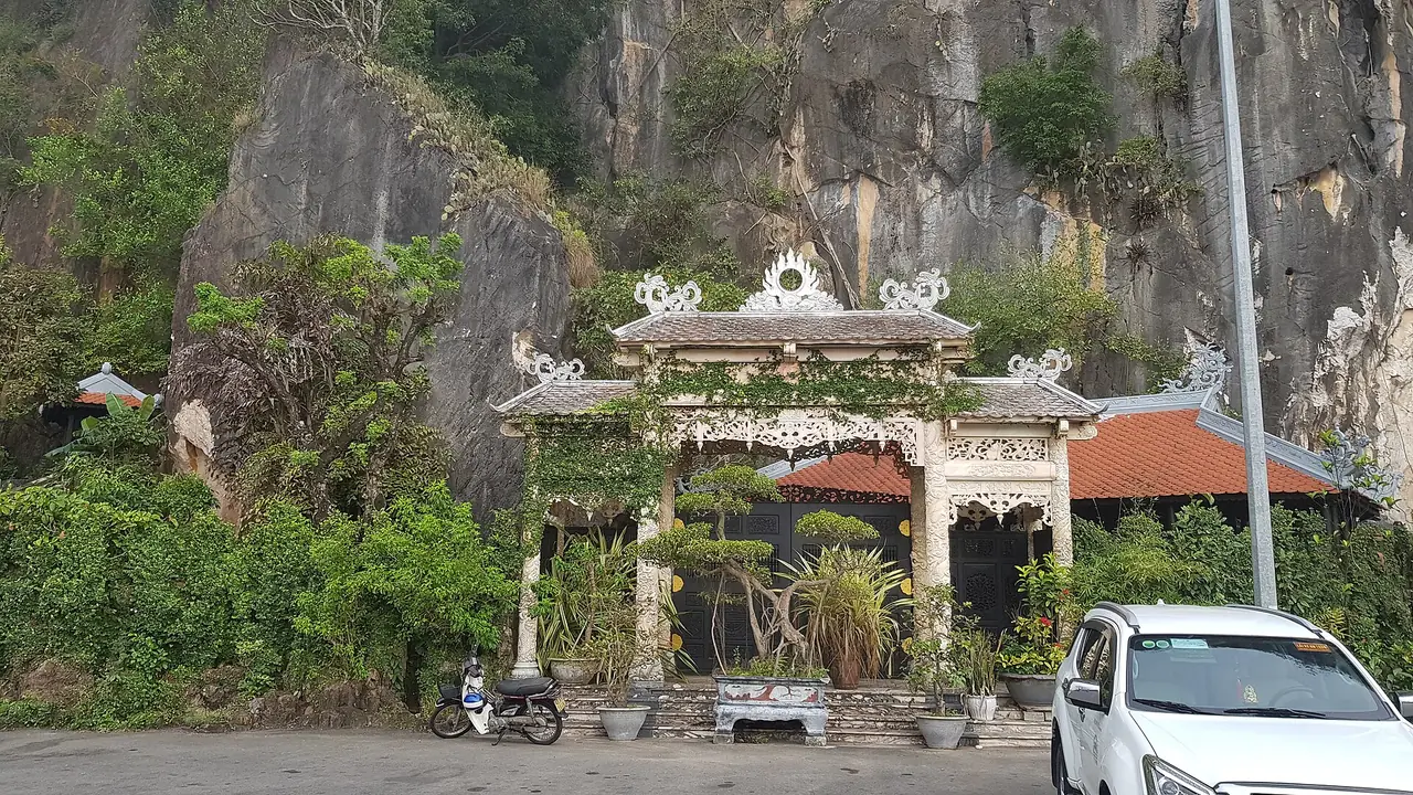 ซุ้มประตูและทางเข้าเขาหินอ่อนท่ามกลางต้นไม้และหน้าผาหิน