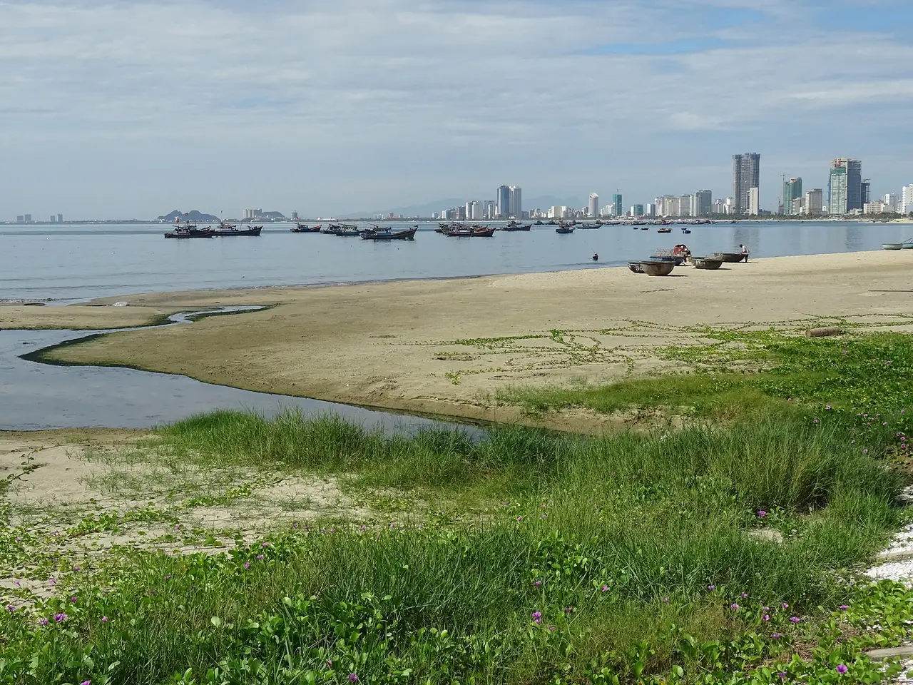 หาดหมีเควยามน้ำลงมีโขดทรายและแนวตึกสูงเป็นฉากหลัง