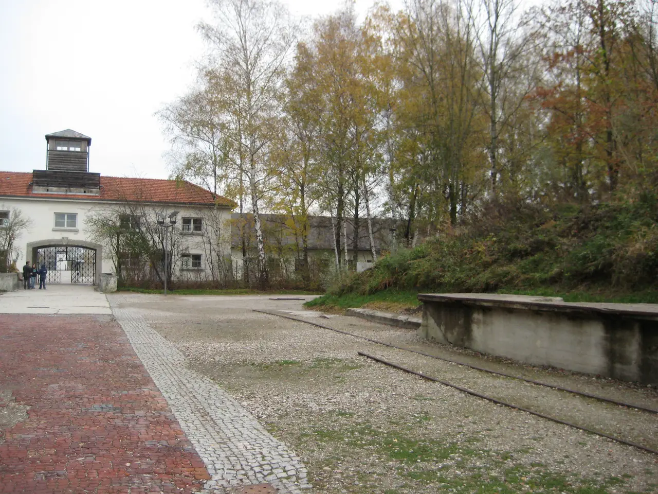 ทางเข้าด้านหน้าและชานชาลารถไฟเดิมที่ดาเคา ภาพถ่ายจาก Wikimedia Commons