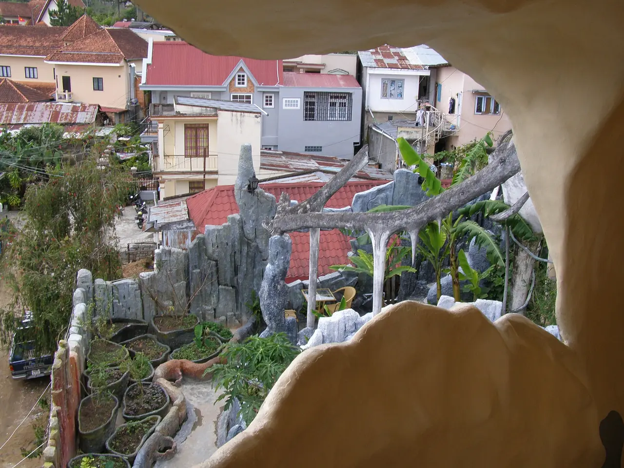 มองจากช่องหน้าต่างรูปถ้ำของ Crazy House ออกไปเห็นหลังคาบ้านและสวนด้านล่าง