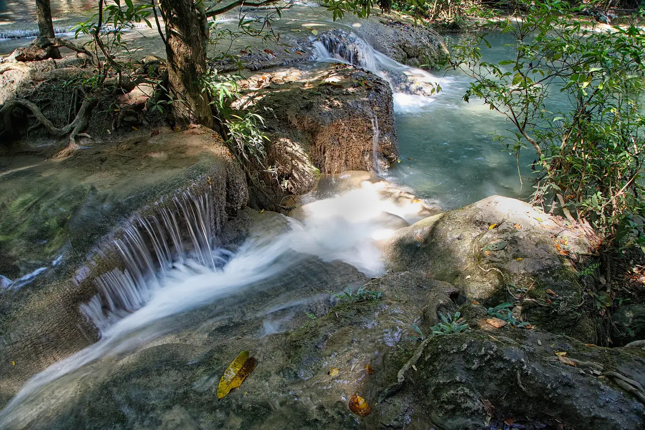 Erawan Falls from the walking path, with swimmers in the pool