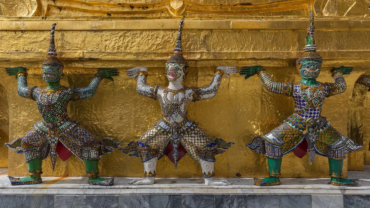 Yaksha guardian statues supporting a golden chedi at Wat Phra Kaew