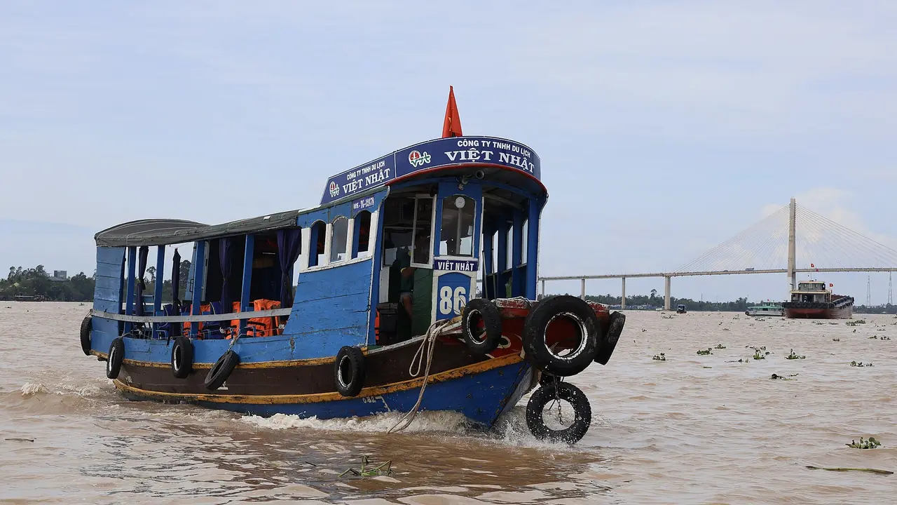 เรือโดยสารในแม่น้ำเตี่ยนที่หมีทอ เห็นสะพานข้ามแม่น้ำไกล ๆ