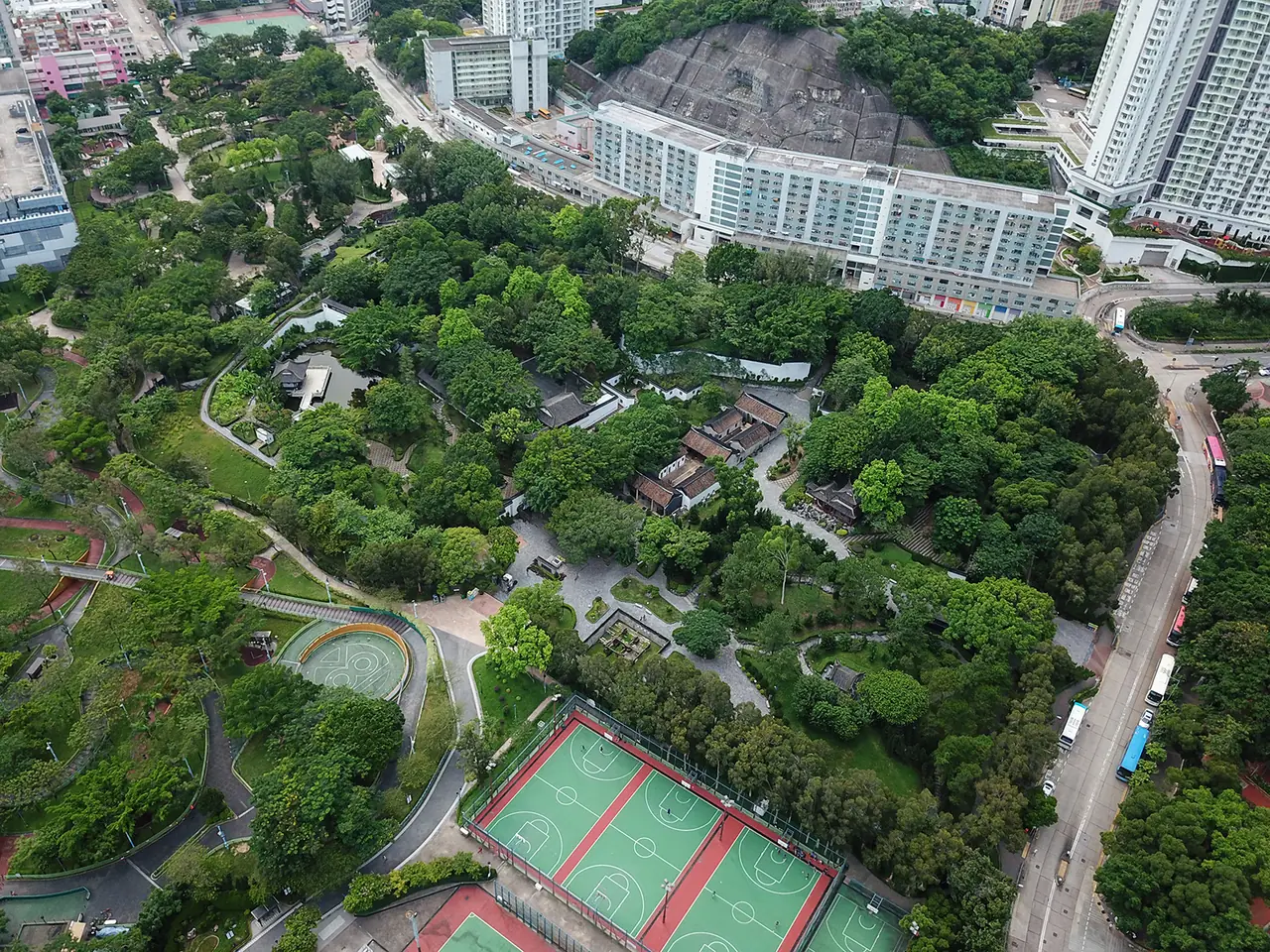 ภาพมุมสูงของสวน Kowloon Walled City Park มองเห็นสนามกีฬา ถนน และอาคารรอบสวน ภาพถ่ายเดือนก.ค. 2561 ภาพจาก Wikimedia Commons ผู้ถ่าย Wpcpey สัญญา CC BY-SA 4.0