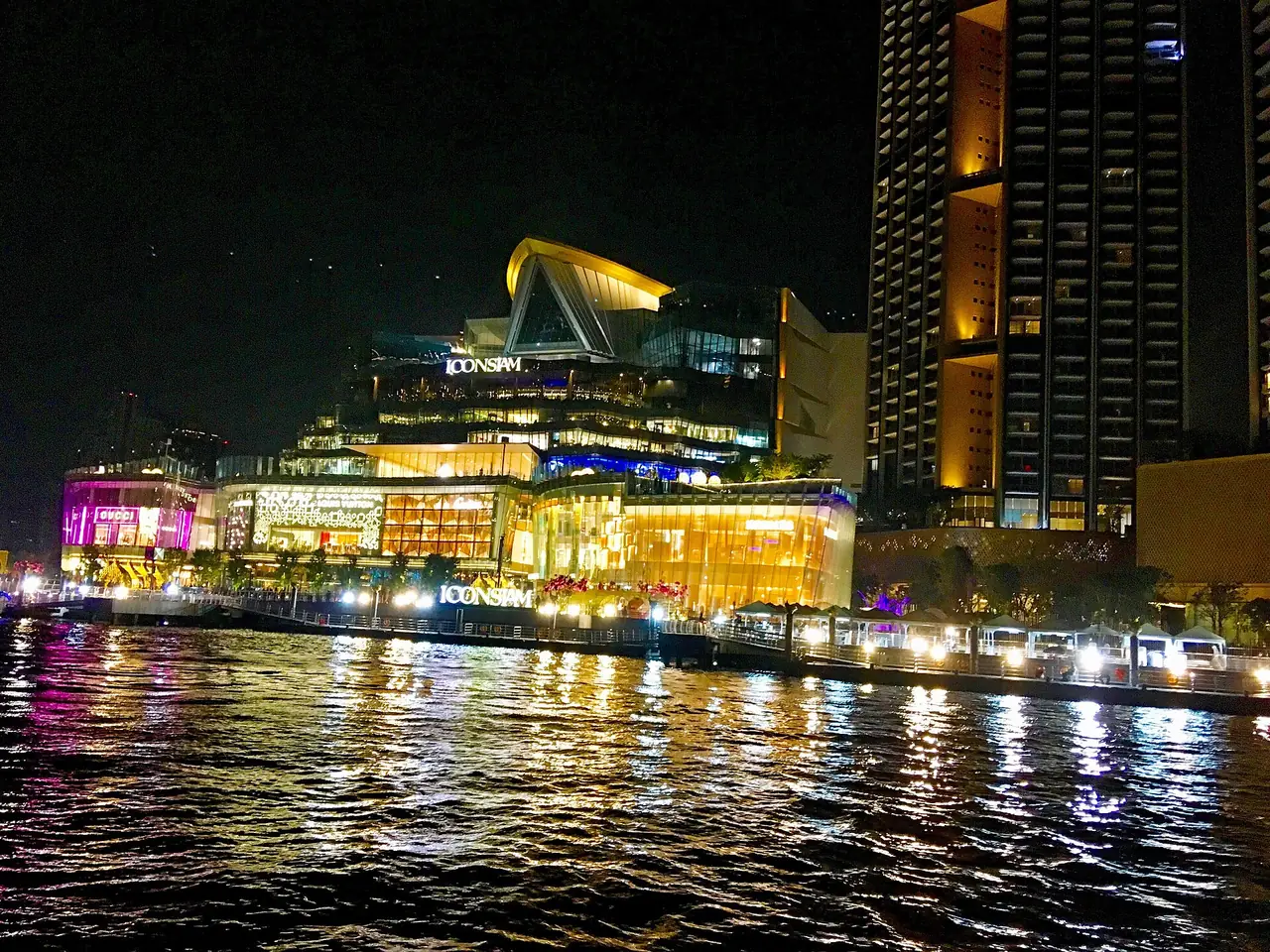 ICONSIAM and the two residential towers lit at night, seen from the Chao Phraya