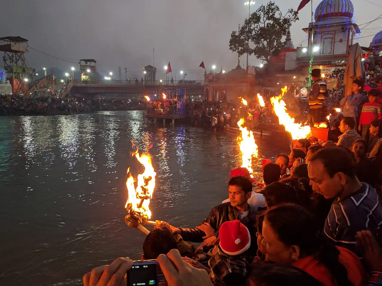 นักบวชและผู้ศรัทธาถือตะเกียงไฟริมน้ำที่ฮาร์กีเปาริ (Har Ki Pauri) หริทวาร ภาพจาก Wikimedia Commons ผู้ถ่าย Ramesh Lalwani สัญญา CC BY 2.0