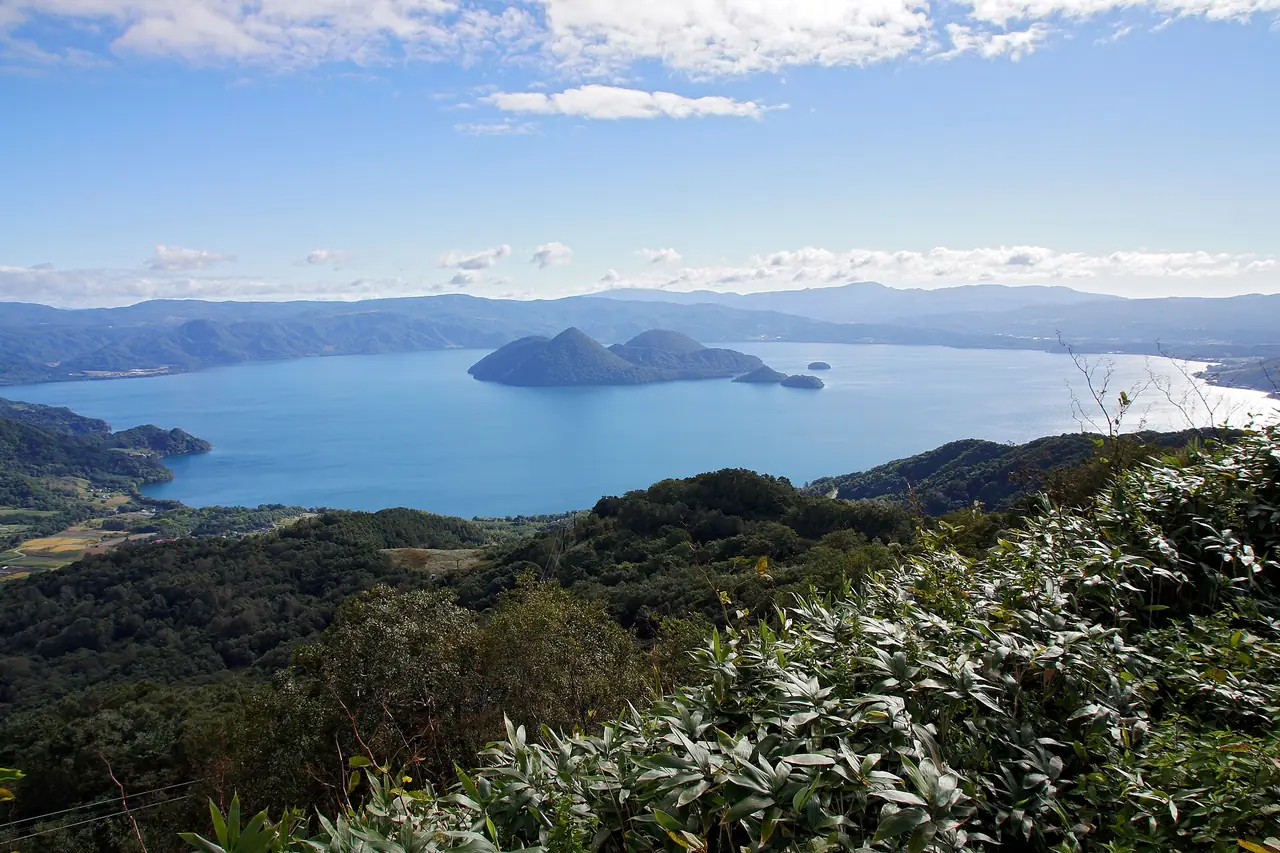 ทะเลสาบโทยะกับเกาะกลางทะเลสาบ มองจากที่สูงริมทะเลสาบ ภาพจาก Wikimedia Commons ผู้ถ่าย 663highland สัญญา CC BY 2.5 ภาพเดือนกันยายน 2556