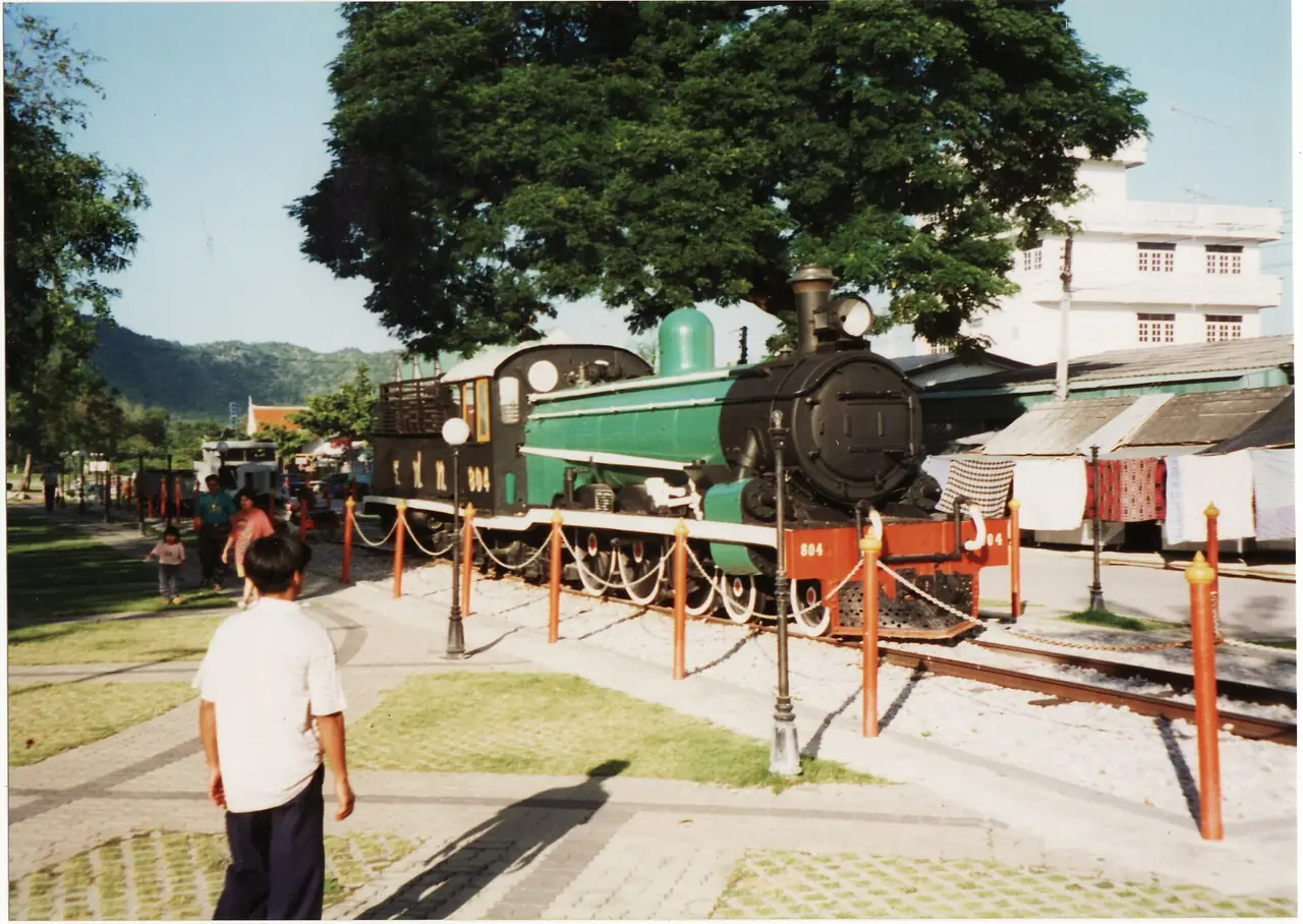 หัวรถจักรไอน้ำจัดแสดงข้างสะพานข้ามแม่น้ำแคว ภาพถ่ายจาก Wikimedia Commons ปี 1996