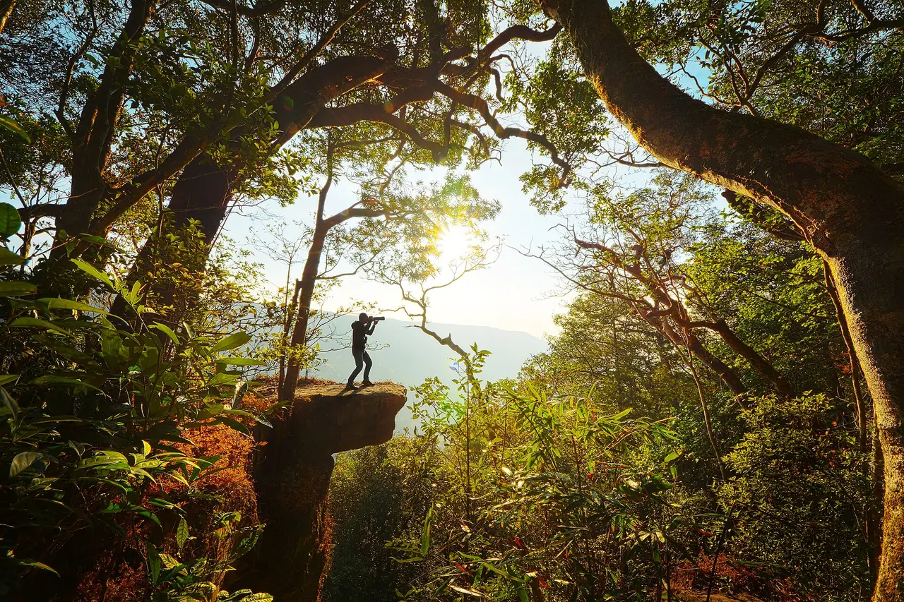 A photographer on a rock ledge at Pha Diao Dai in Khao Yai National Park