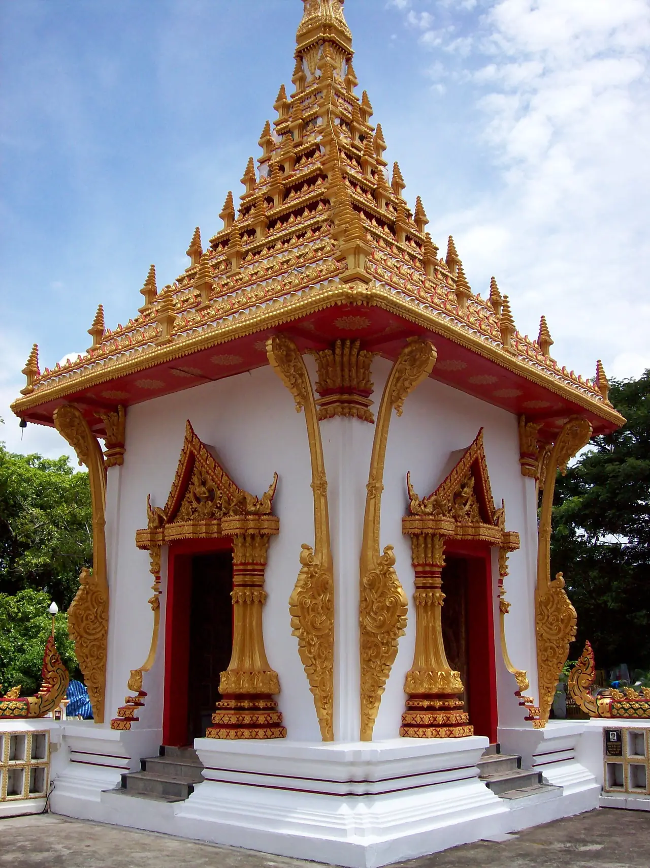 อาคารมุมหนึ่งบนฐานพระธาตุที่มีหลังคาซ้อนชั้นสีทองและประตูสีแดง ภาพถ่ายจาก Wikimedia Commons