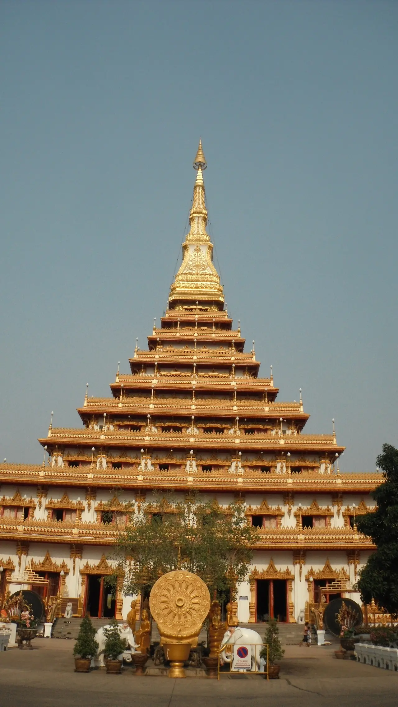 พระธาตุเก้าชั้นและลานด้านหน้าที่มีรูปปั้นและป้าย ภาพถ่ายจาก Wikimedia Commons