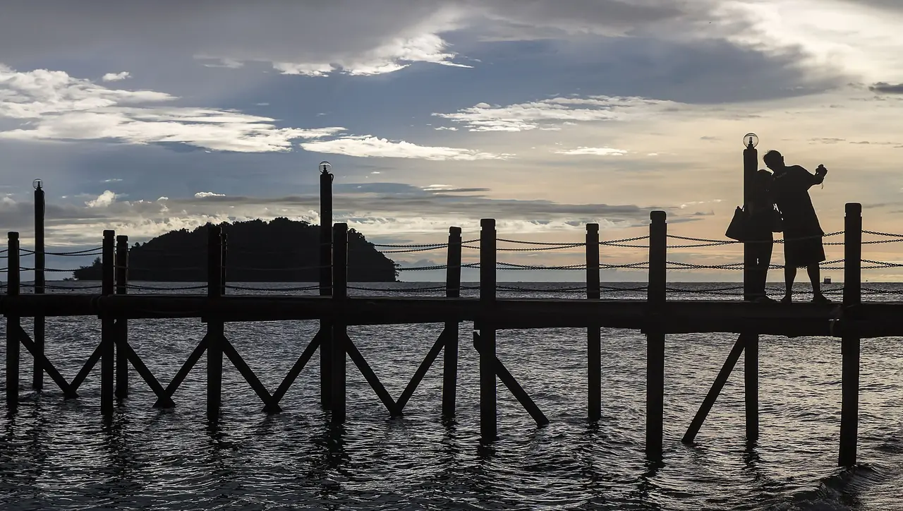 ท่าเทียบเรือไม้บนเกาะมานูกัน มองเห็นเกาะอีกเกาะอยู่ไกลออกไปยามเย็น (ภาพบรรยากาศ)