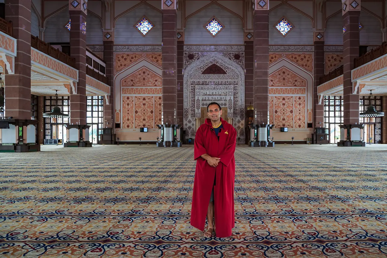 ผู้มาเยือนสวมชุดคลุมที่ต้องใส่ภายในมัสยิดปุตรา ตามคำอธิบายภาพบน Commons