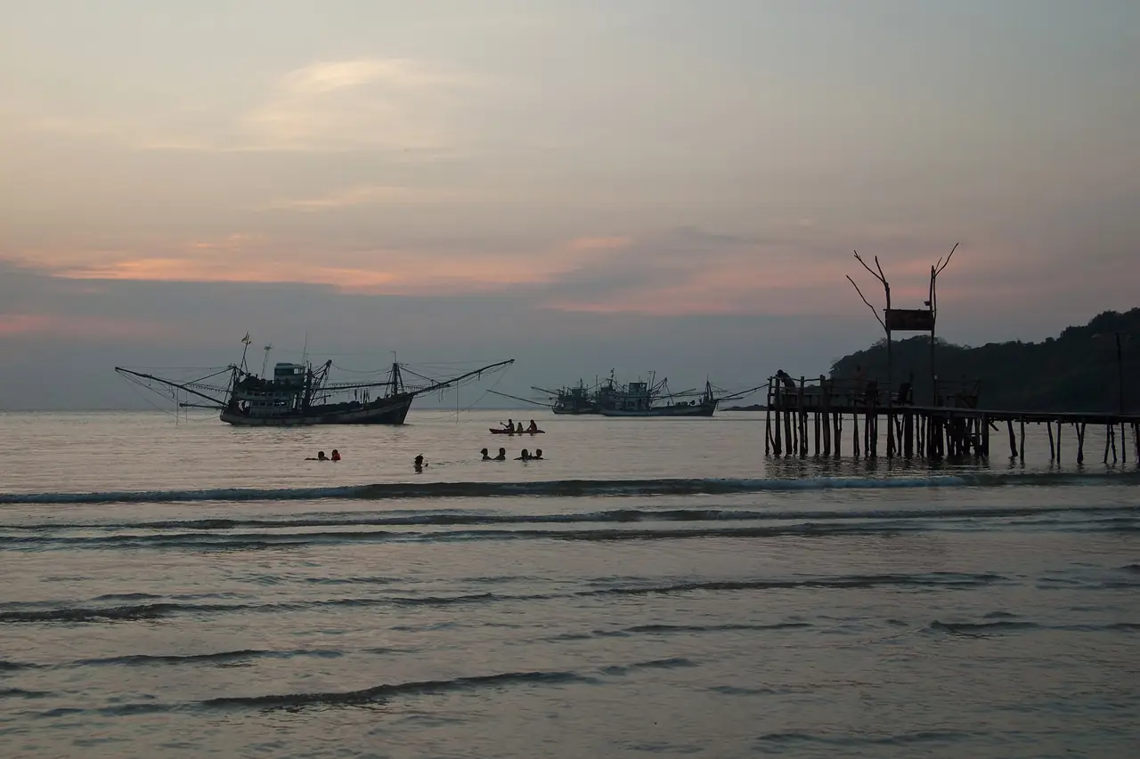 Fishing boats and a wooden pier at dusk on the Gulf of Thailand