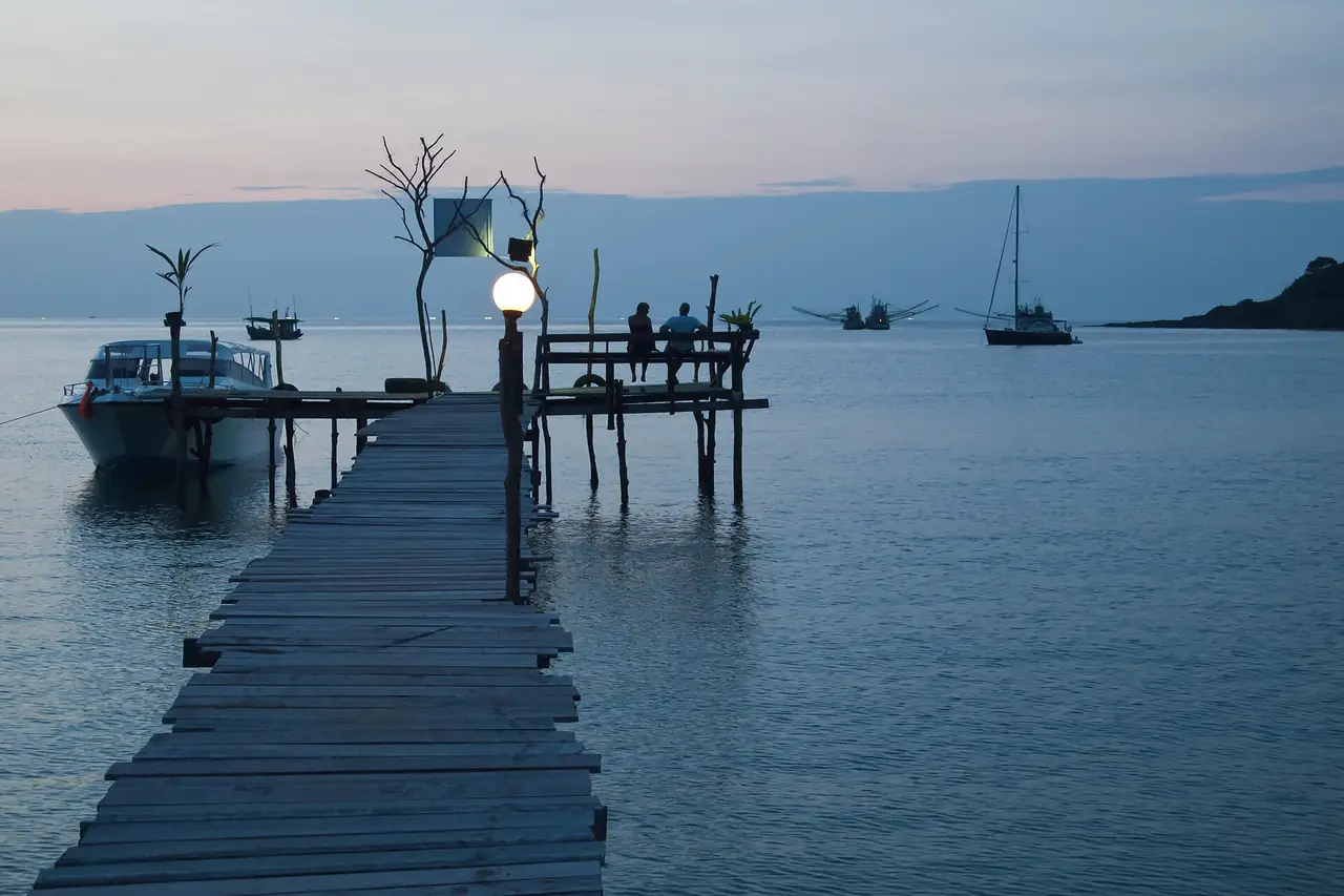สะพานท่าเรือบนเกาะกูดยามพลบค่ำ มีเรือเล็กจอดเทียบ ตามคำบรรยายภาพบน Commons เป็นภาพอ่าวบางเบ้า ไม่ใช่ท่าเรือโดยสารหลัก ภาพของ Vyacheslav Argenberg จาก Wikimedia Commons