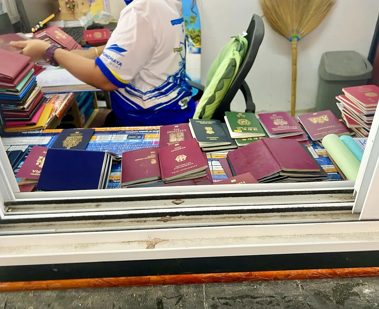 เจ้าหน้าที่เสื้อบัณฑหยารวมหนังสือเดินทางผู้โดยสารเป็นกองที่เคาน์เตอร์ ภาพปี 2568 จาก Wikimedia Commons ผู้ถ่าย Sharon Hahn Darlin ไม่ระบุจุดแน่ชัด