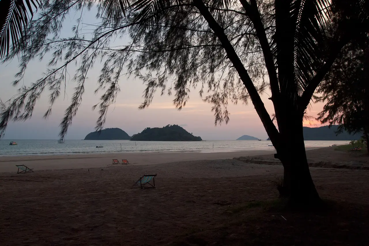 หาดทรายและเก้าอี้ผ้าใบใต้ต้นสน เห็นเกาะเล็กไกล ๆ ตอนพลบค่ำบนเกาะหมาก ภาพของ Vyacheslav Argenberg จาก Wikimedia Commons ตามคำบรรยายภาพบน Commons เป็นหาดบนเกาะหมาก ไม่ได้ระบุว่าเป็นท่าเรือ