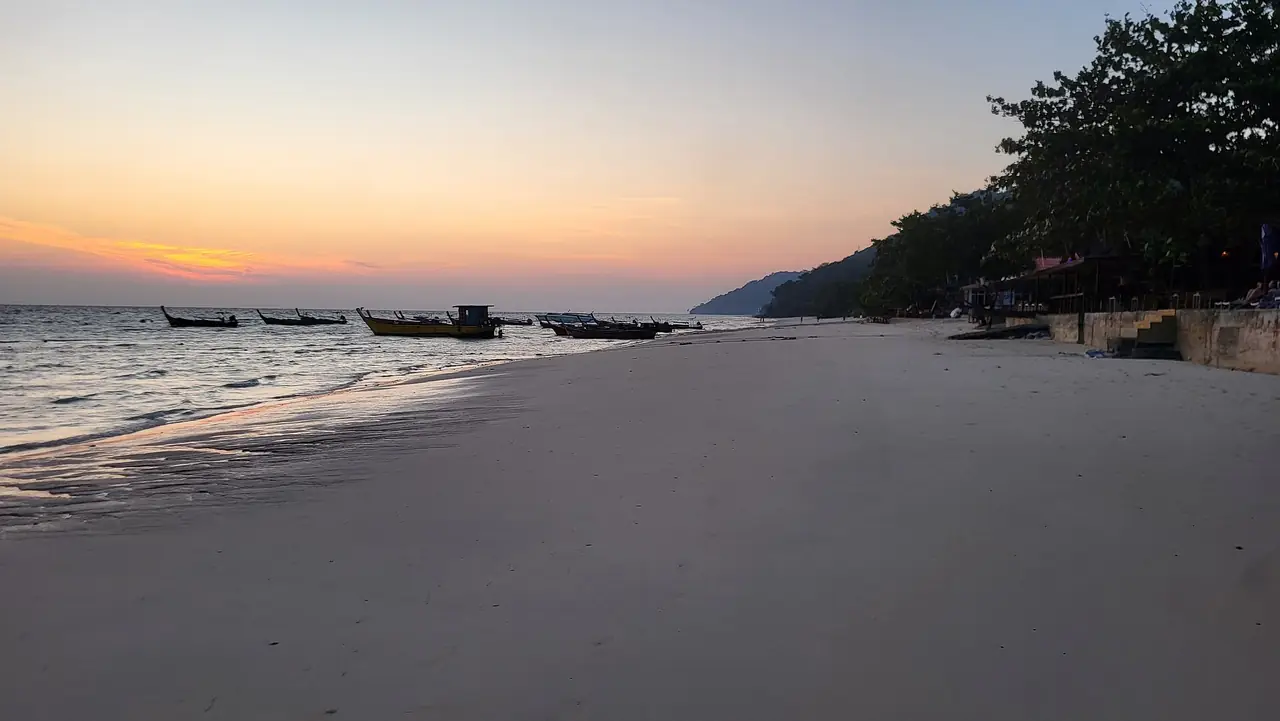 ชายหาดบนเกาะพีพีดอนตอนพระอาทิตย์ตก มีเรือหางยาวจอดไกล ๆ ภาพถ่ายต้นปี 2568 ผู้ถ่ายไม่ได้ระบุว่าเป็นหาดใด เป็นภาพประกอบ ภาพถ่ายจาก Wikimedia Commons