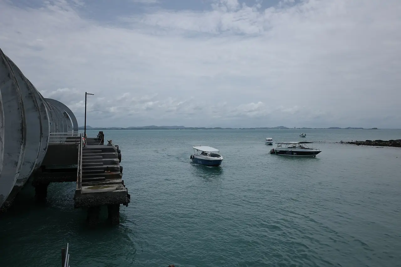 ท่าเทียบเรือหน้าด่านมองออกไปทะเล มีเรือเร็วลำเล็กจอดนอกท่า ภาพถ่ายจาก Wikimedia Commons