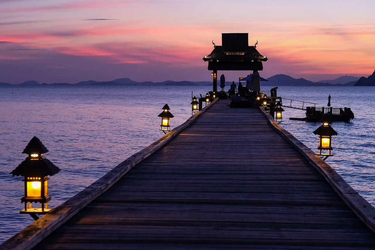 สะพานท่าเรือไม้ประดับโคมไฟยื่นลงทะเลตอนพลบค่ำ ภาพ CC0 ของ Alin Meceanu จาก Wikimedia Commons ตามชื่อภาพเป็นท่าเรือเกาะยาวใหญ่ ใช้เป็นภาพประกอบ ไม่ได้ระบุท่าเรือโดยสาร