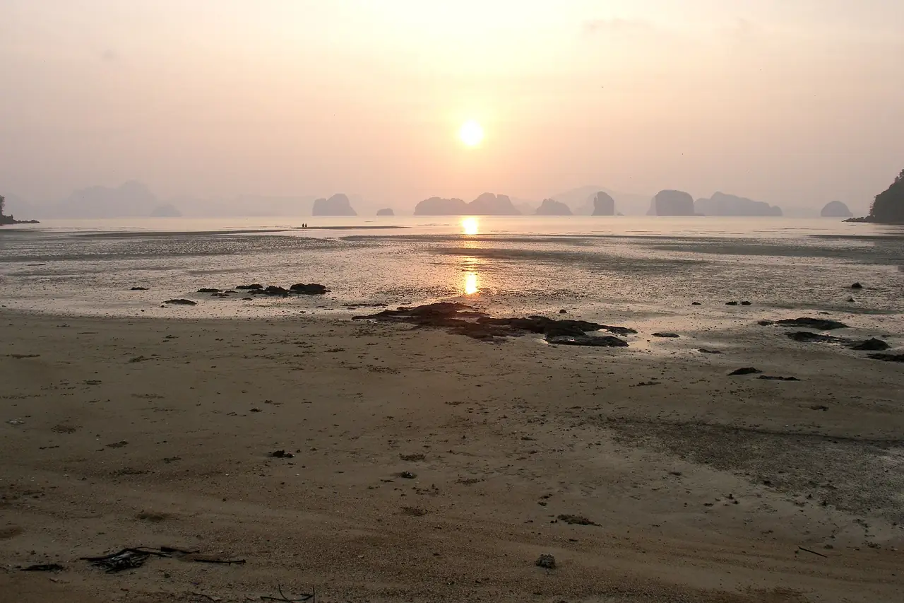 หาดโคลนทรายตอนน้ำลงและพระอาทิตย์ขึ้นเหนือเกาะหินปูนในอ่าวพังงา ภาพของ Vyacheslav Argenberg จาก Wikimedia Commons ตามคำบรรยายภาพบน Commons เป็นพระอาทิตย์ขึ้นบนหาดของเกาะยาวน้อย ไม่ได้ระบุชื่อหาด