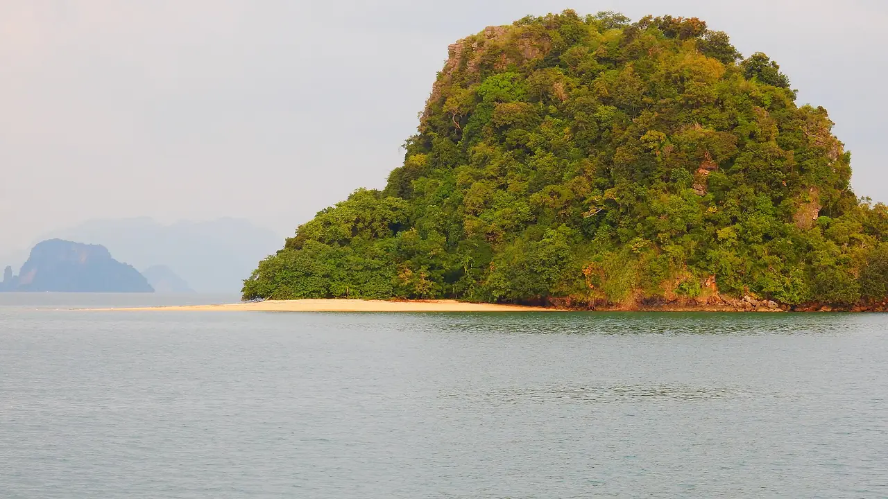 เกาะหินปูนเล็กที่มีป่าเขียวและแนวหาดทรายเตี้ย มองจากเรือในอ่าวพังงา ภาพของ Roma Neus จาก Wikimedia Commons ถ่ายเมื่อ ธ.ค. 2557 ตามคำบรรยายภาพบน Commons เป็นภาพจากเกาะยาวน้อย ไม่ได้ระบุว่าเป็นเกาะไหน