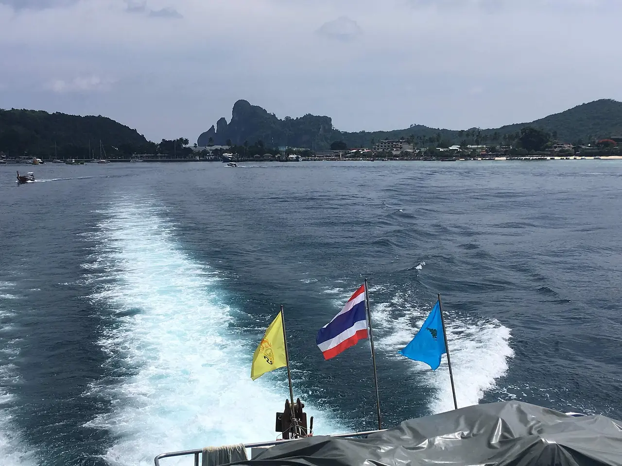 อ่าวต้นไทรบนเกาะพีพีดอนถ่ายจากท้ายเรือ มีเรือเล็กจอดในอ่าว ปลายทางหลักของเรือจากกระบี่