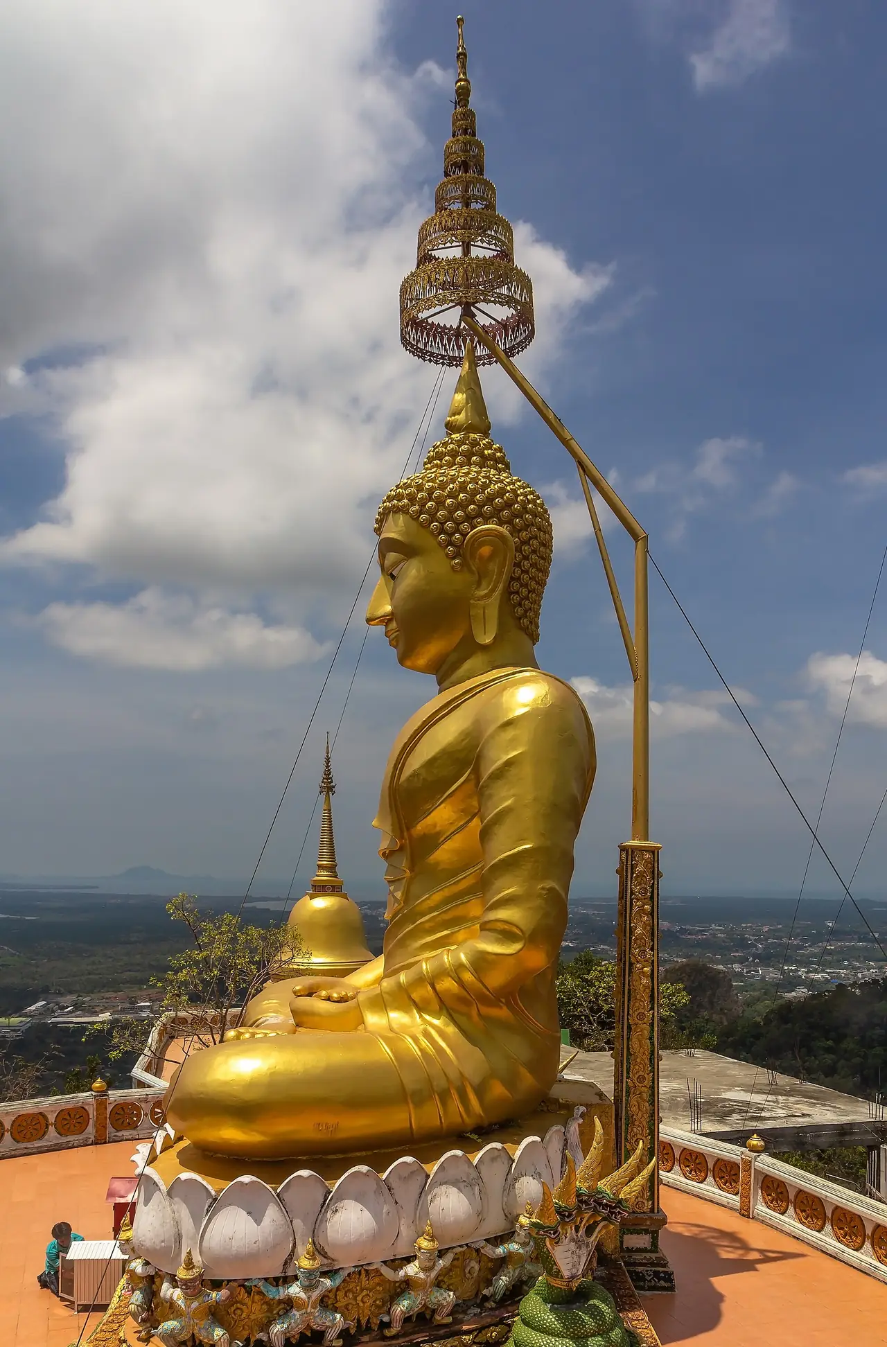 พระพุทธรูปทองบนลานชมวิวที่ยอดเขา มองเห็นที่ราบรอบเมืองกระบี่ ภาพถ่ายจาก Wikimedia Commons