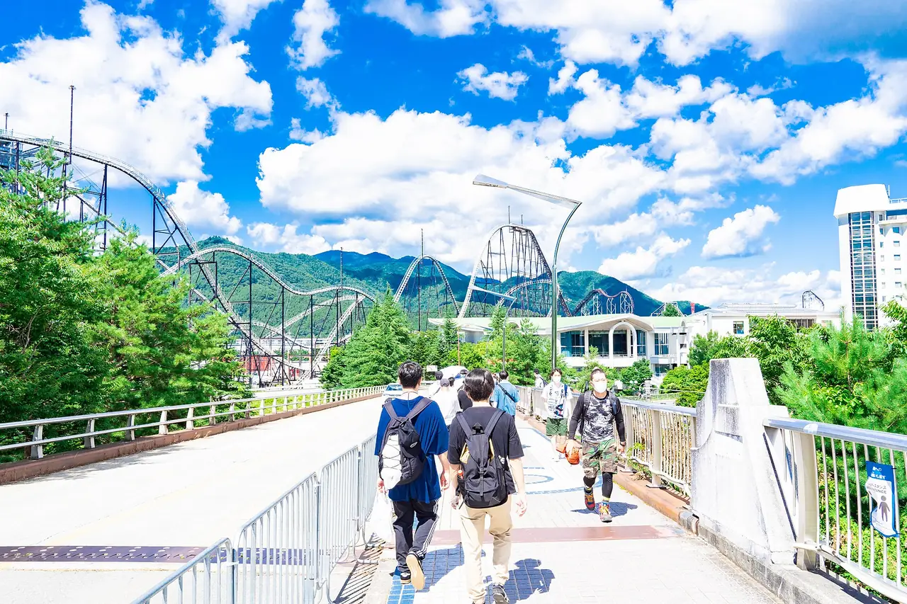 ทางเดินเข้าสวนสนุกพร้อมรางรถไฟเหาะด้านหลัง (ภาพทางเข้า)